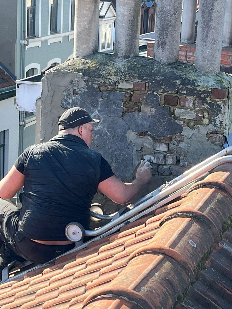 Cheminée à Auderghem avant restauration, montrant l'usure, les fissures et les dommages.